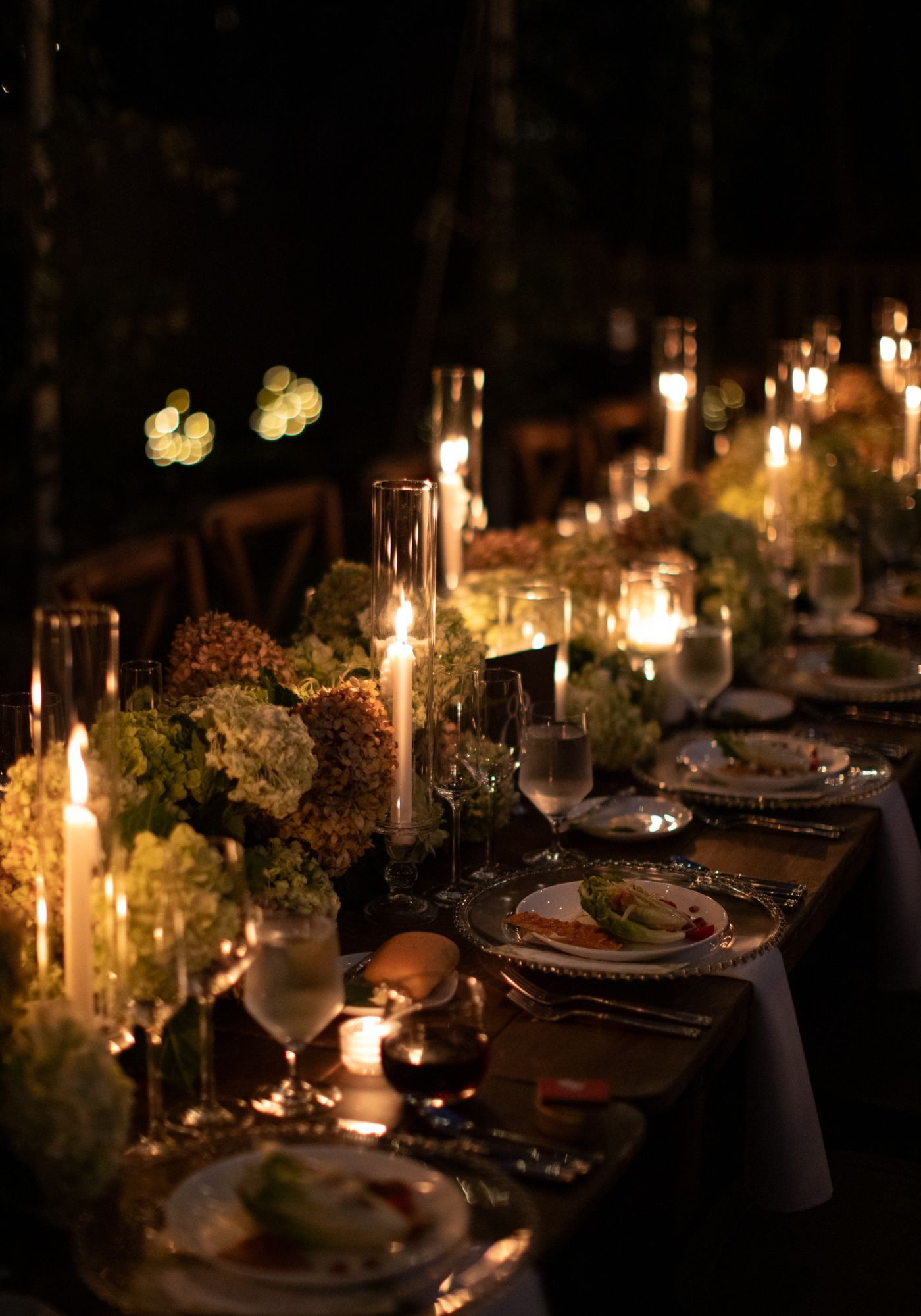 Elegant dining table set with candles and floral arrangements, creating a cozy atmosphere for an evening dinner.